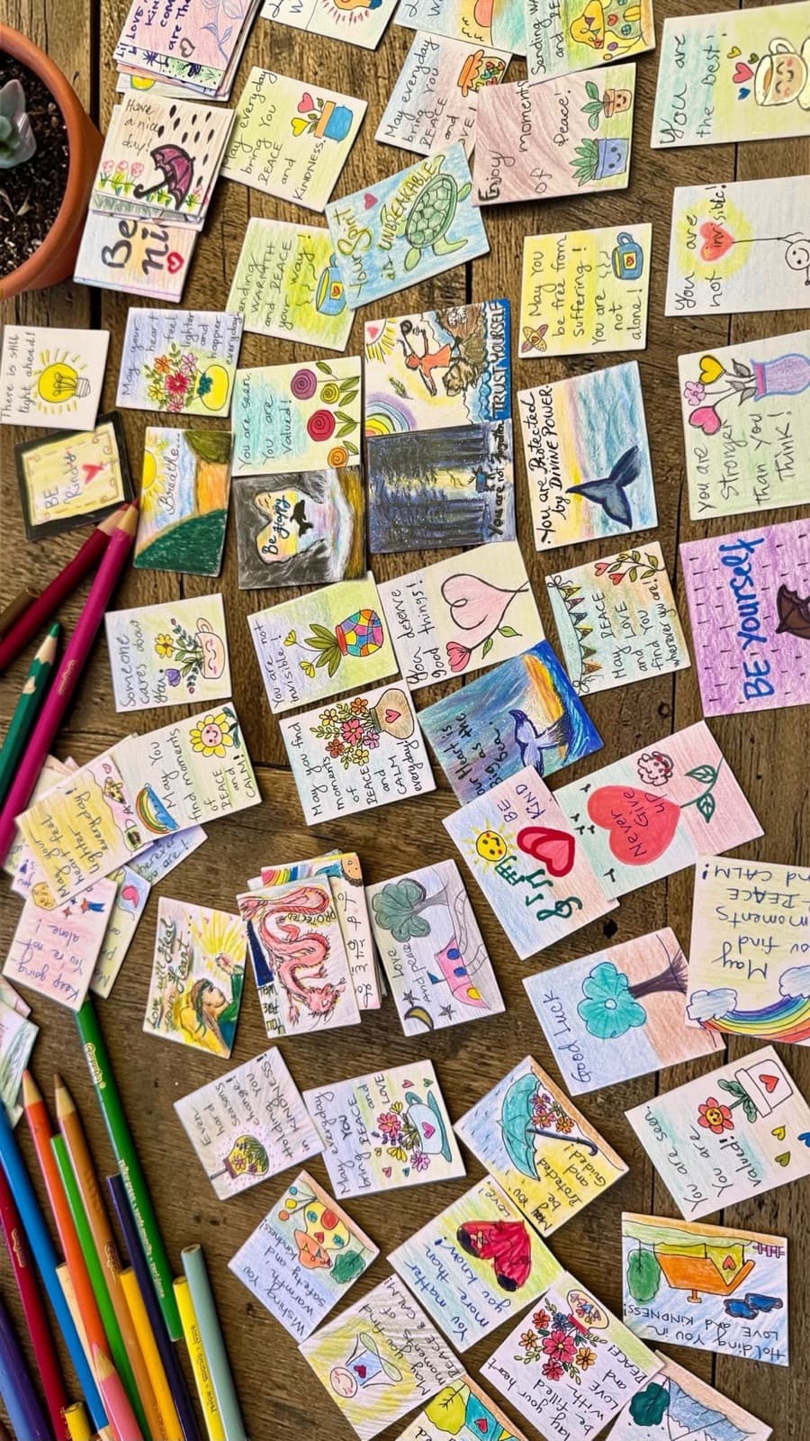 Dozens of kindness cards covering a wooden table.