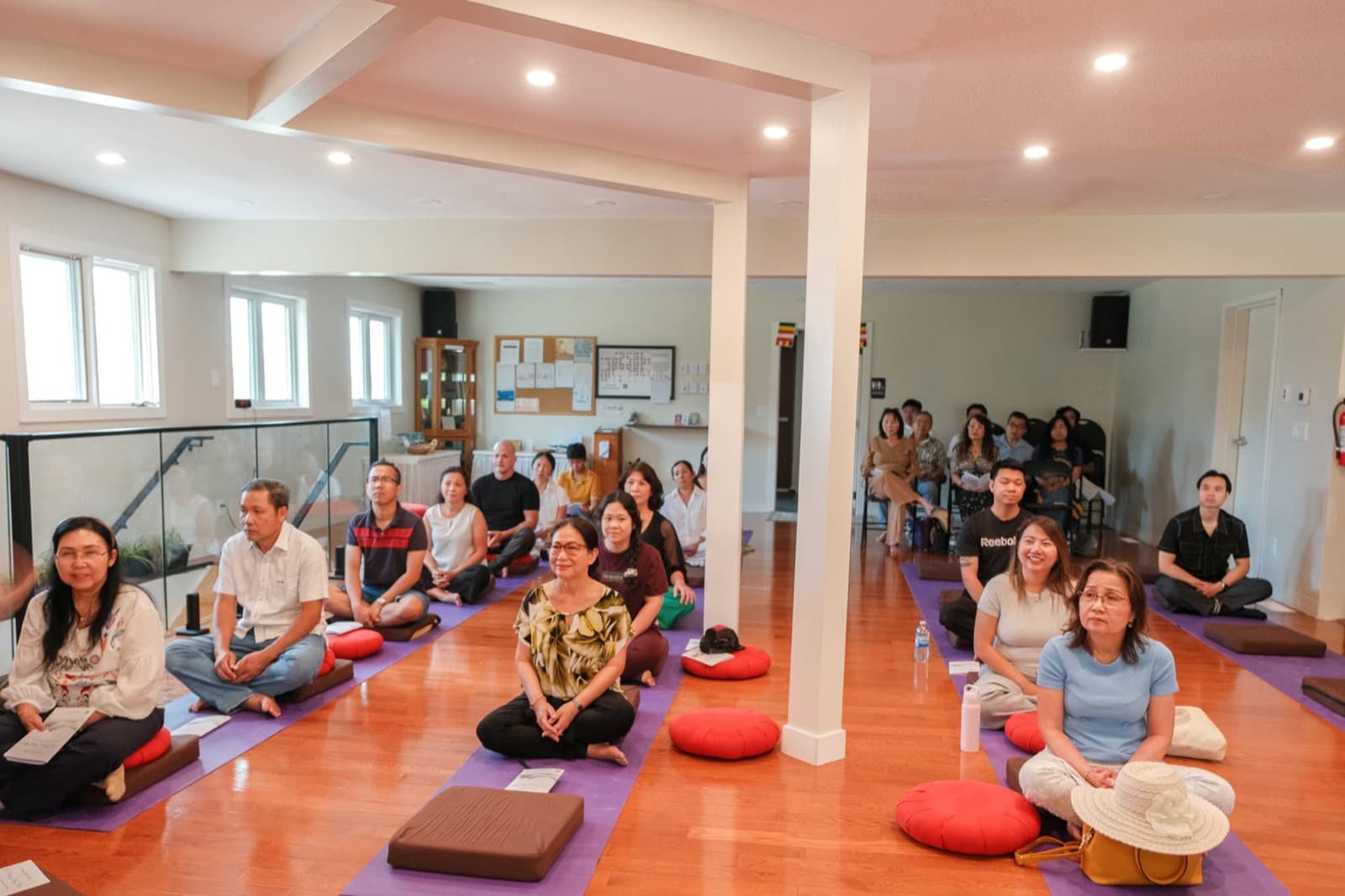 Participants sitting in meditation on mats in a sunlit room.